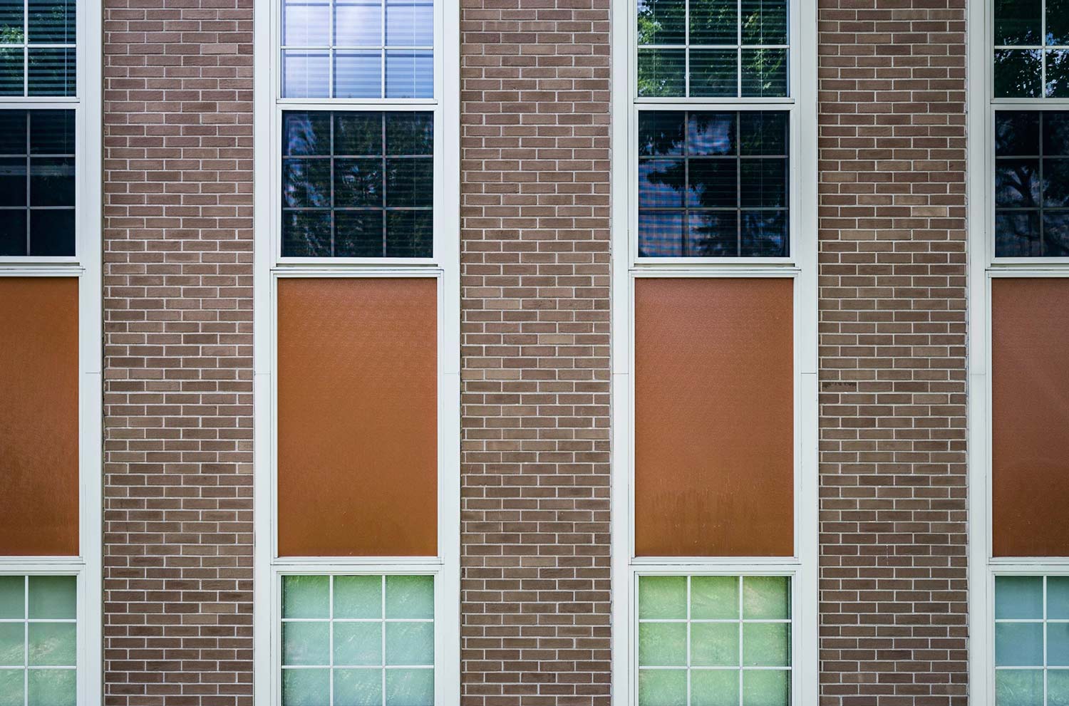 Outside wall of an industrial-looking building, with rows of windows and bricks