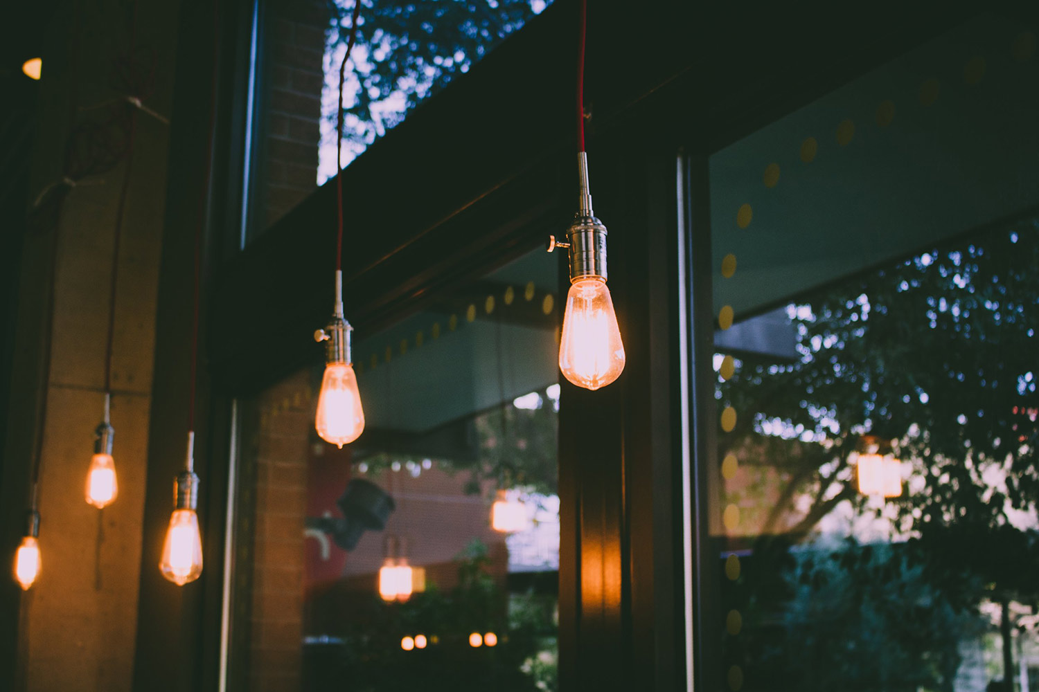 boozy-work-event Trendy Edison bulbs hang in a restaurant.