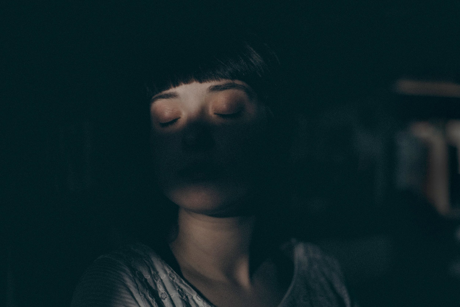 A woman's face with heavy shadows obscuring it