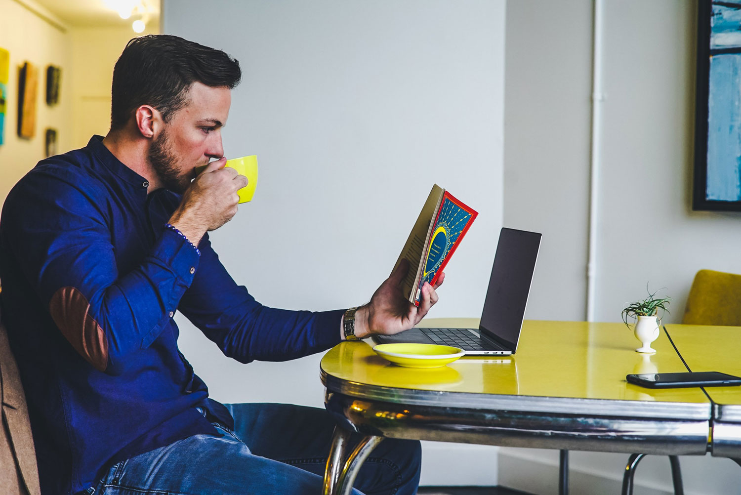 chris-benson-575510-unsplash A man reads a book while drinking coffee