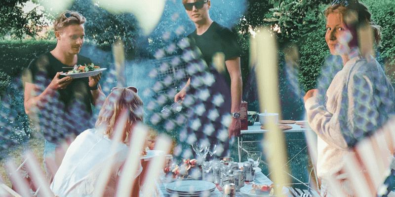 Blog_4thOfJuly People at an outdoor barbecue. The image is overlaid with American flags.